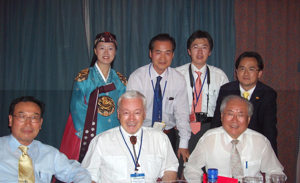 Na zdjęciu widać siedem os&oacute;b, sześć z nich ma skośne oczy. Trzy osoby siedzą, trzy stoją. Jedyna kobieta w tym gronie jest ubrana w tradycyjny azjatycki str&oacute;j.